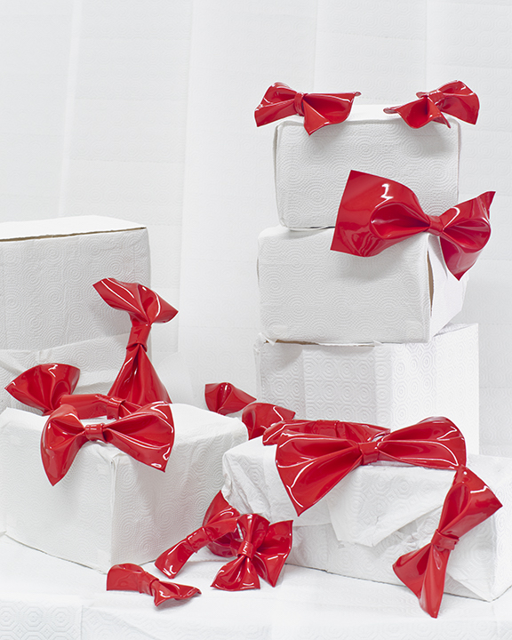 shiny red bows adorn a pile of wrapped white boxes
