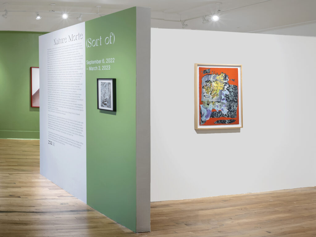 A photograph of Hunt-Cavanagh Gallery at Providence College showing a T shaped wall with a wall behind it. Portions are painted a bright green and 3 artworks can be seen hanging on the walls.
