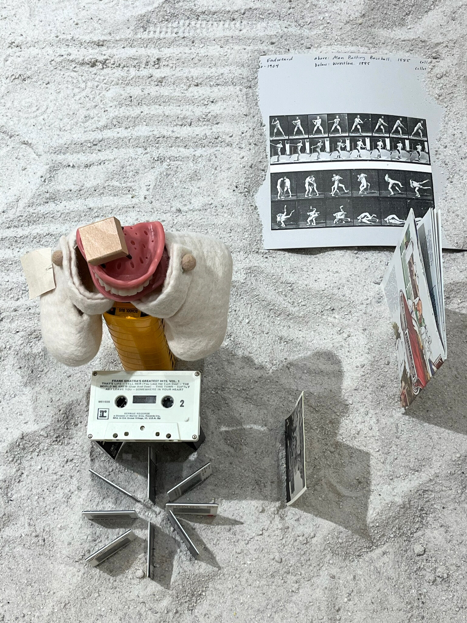 Antique everyday items, including a comb and a pill jar, protrude from a pristine white surface, each object frozen mid-emergence from the table.