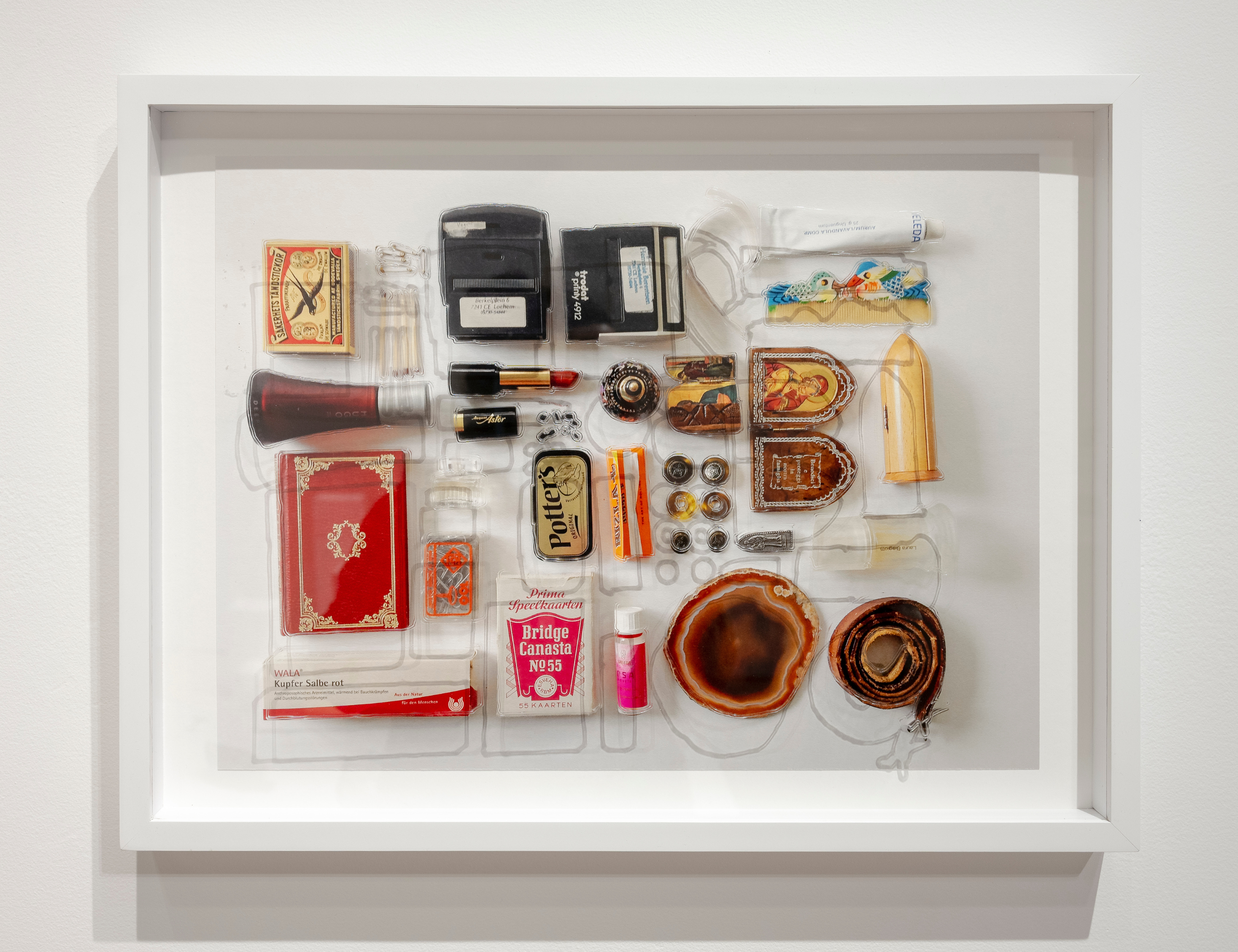 Various every day items including lipstick, haircomb, belt, card box arranged against a white background.