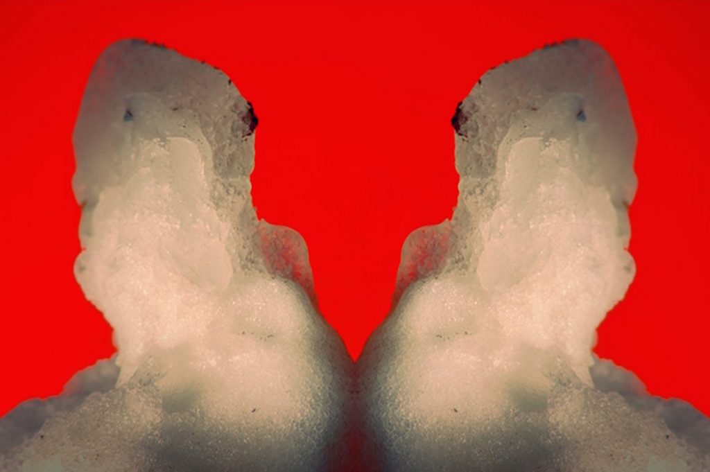 photograph of two amorphous shapes on a bright red background