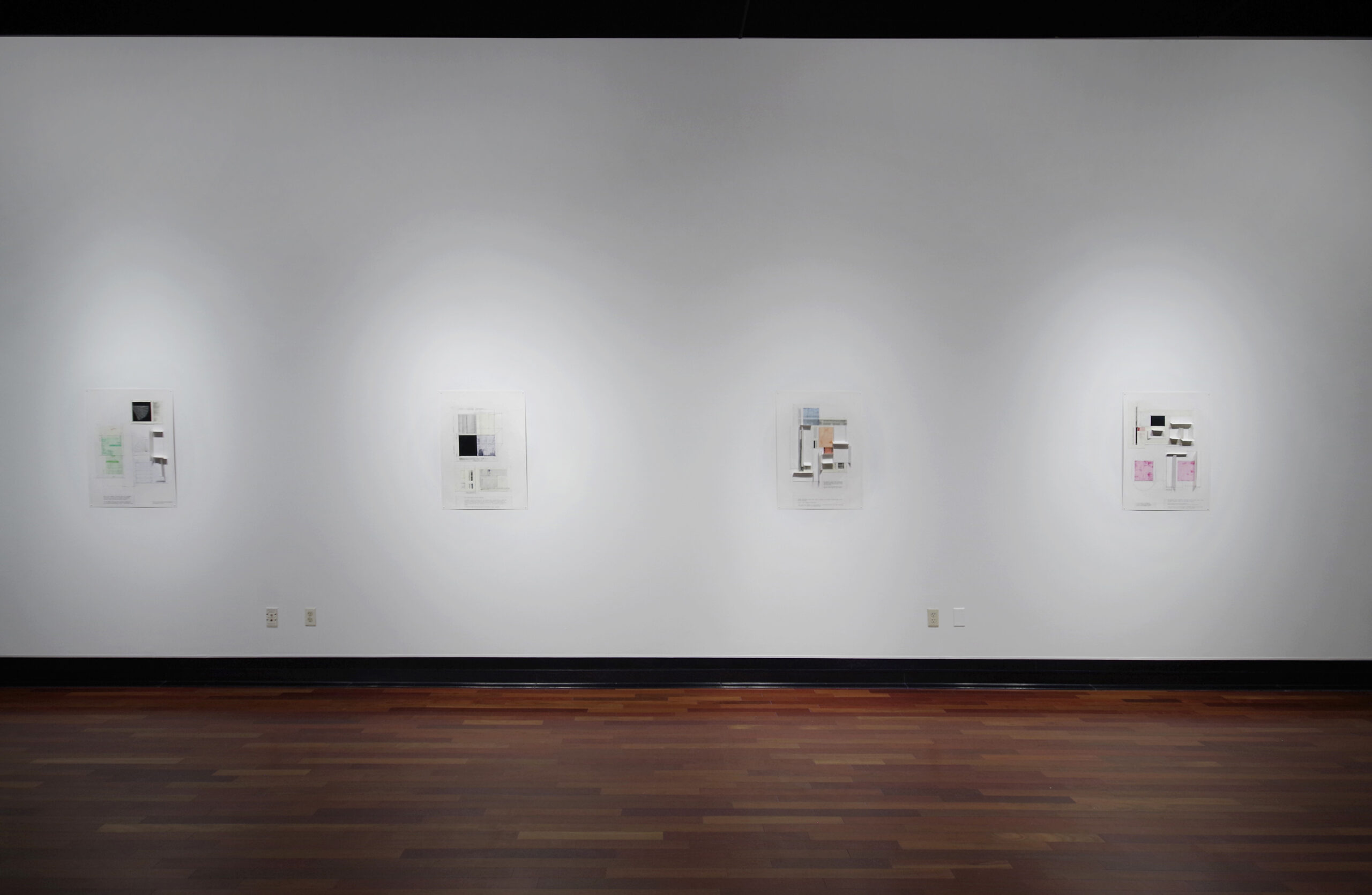A white gallery wall holding four prints with multicolor squares and rectangles present on each one.