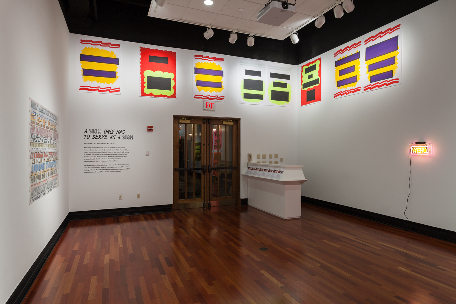 Installation view of an empty gallery with eight abstract artworks spanning across the tops of two walls. Double doors are next to wording on the wall, reading A SIGN ONLY HAS TO SERVE AS A SIGN.