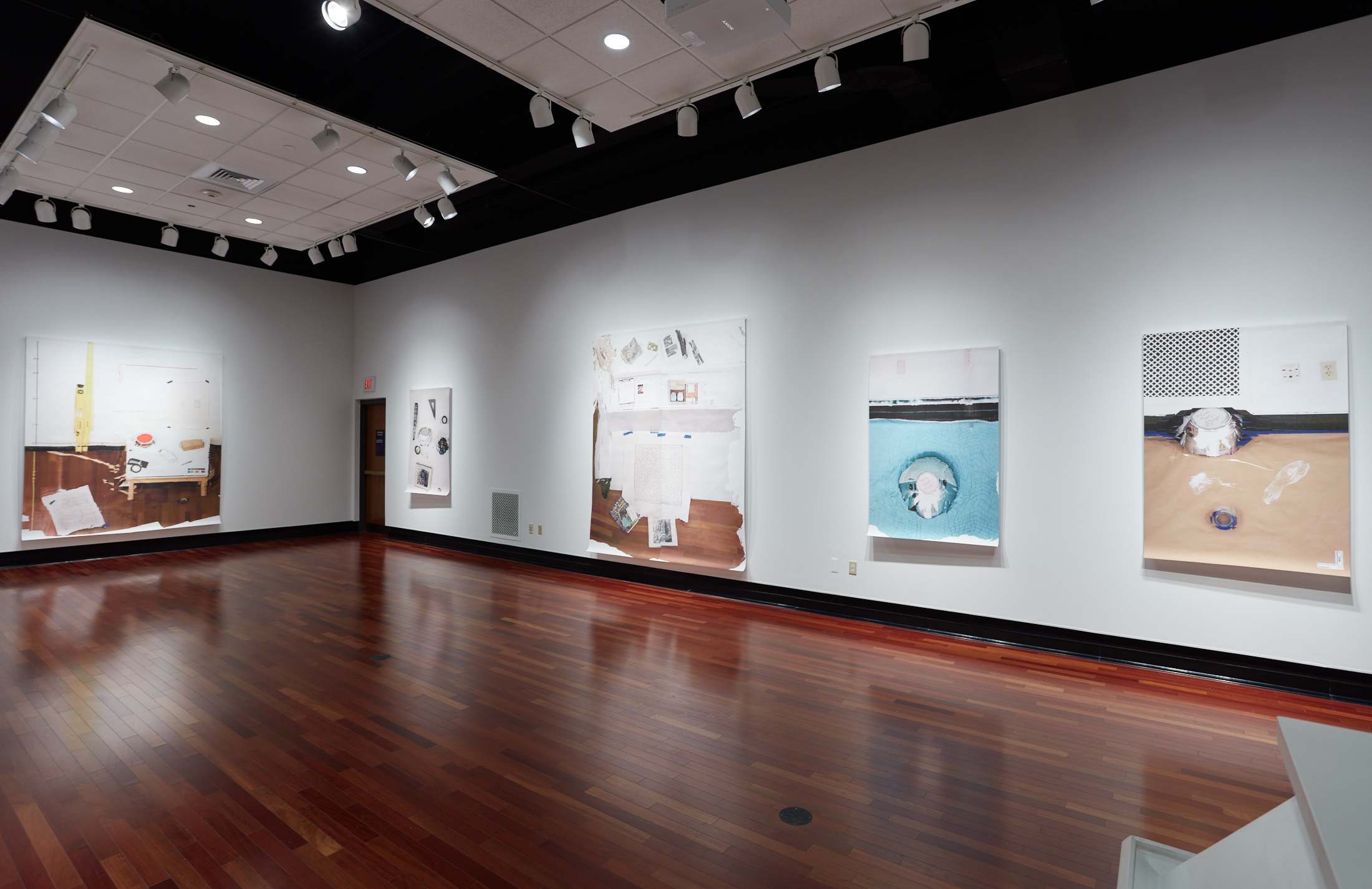 Two white walls; the back wall displays a large canvas, while the right wall holds four paintings depicting studio scenes.