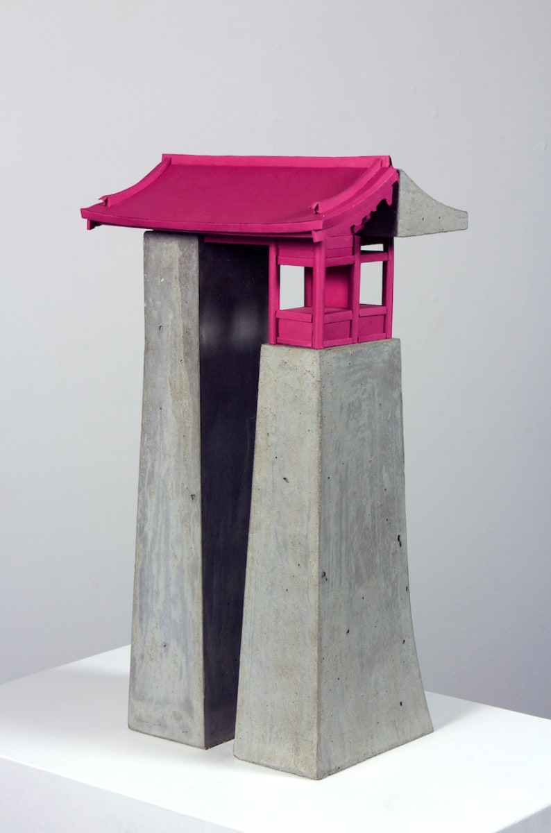 A sculpture of a vertical architectural form mostly made of grey concrete. Half of the roof and the front facade are hot pink.