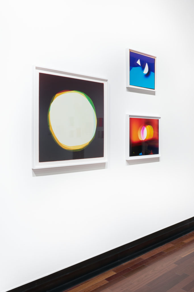 Gallery wall featuring three abstract prints of geometric shapes with slightly colored edges, suggesting the artist was playing with color registration.