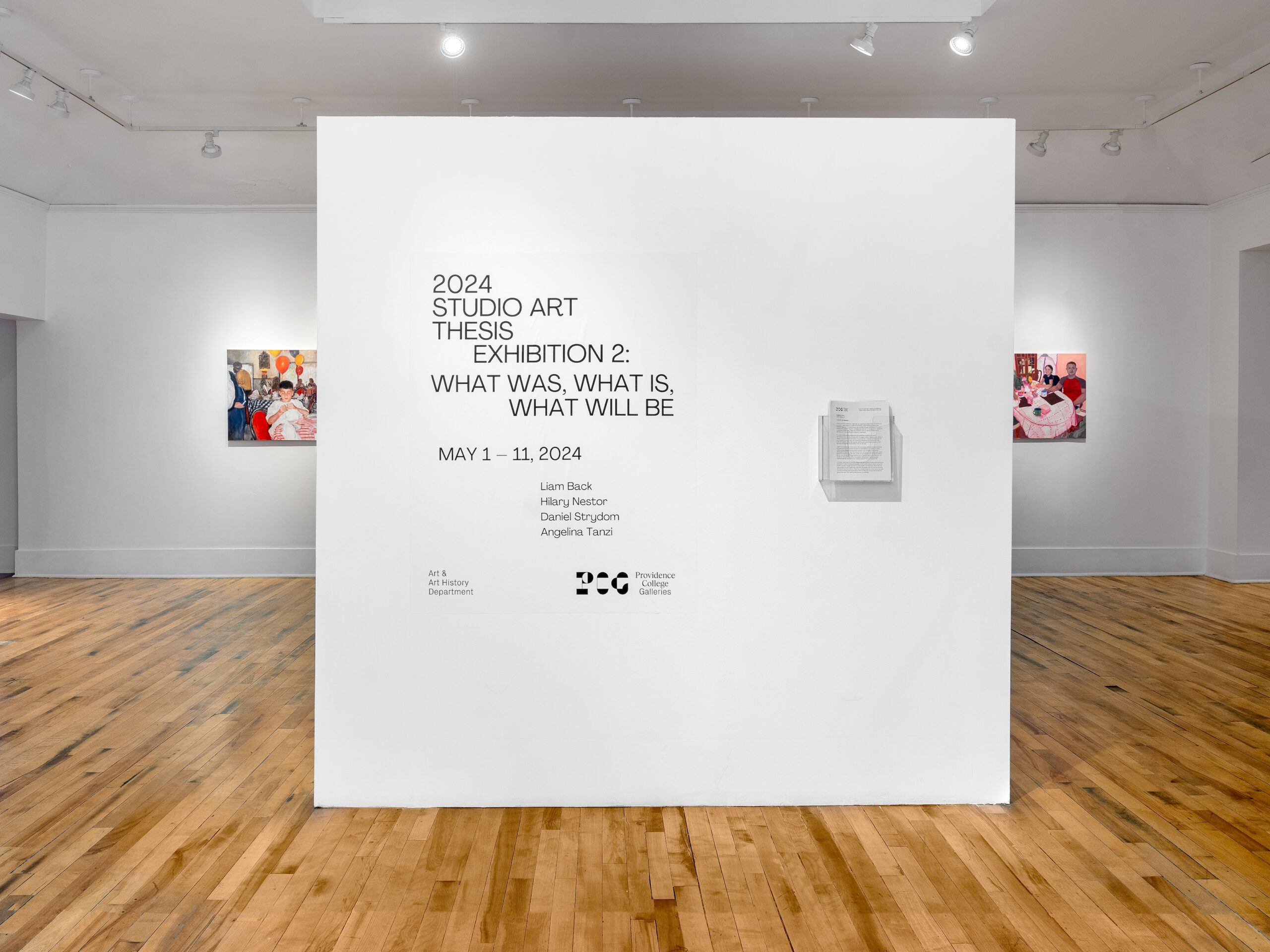 An installation view of a gallery with a white wall reading: 2024 Studio Art Thesis Exhibition 2: What Was, What Is, What Will Be. On either side of the wall, artwork is visible in the background.