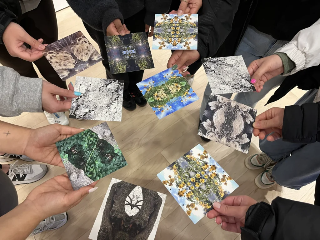 Students in a circle, holding out nature-oriented post cards.
